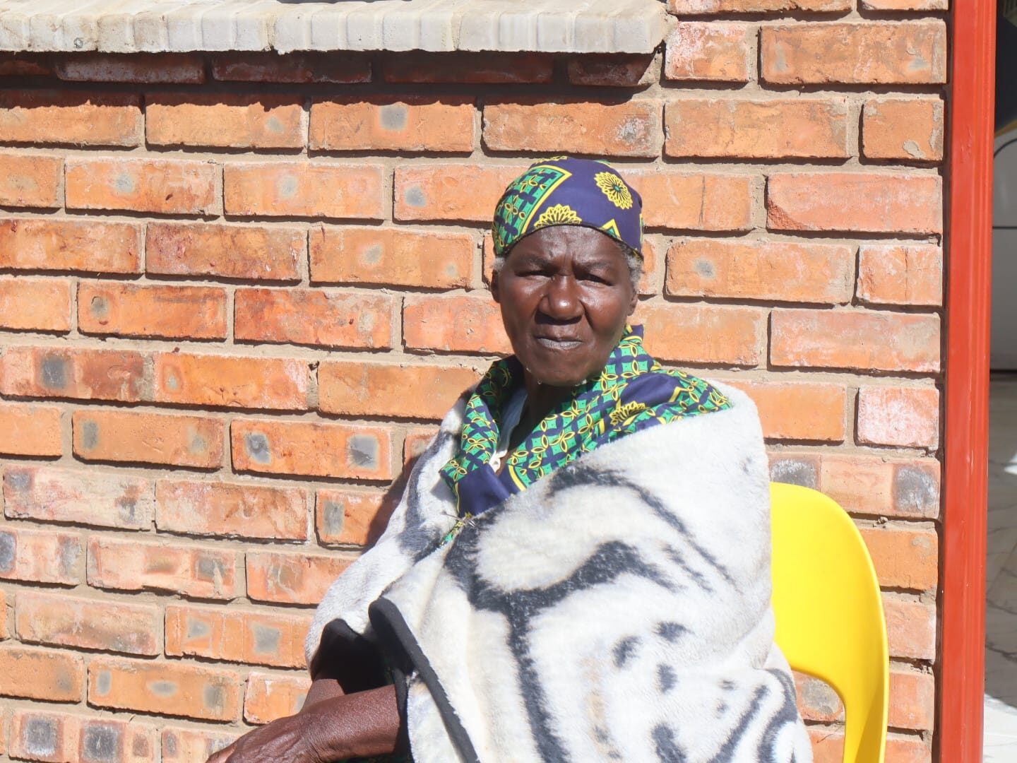 75 year old Maria Maleroele Malakoane sitting in front of her new house